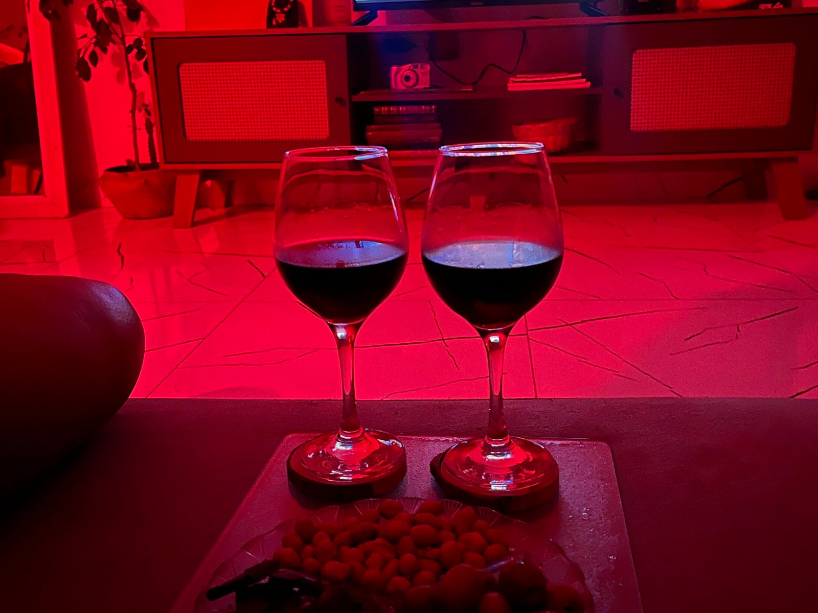 A couple snuggled on the couch under a blanket, surrounded by popcorn and snacks, enjoying a movie night at home